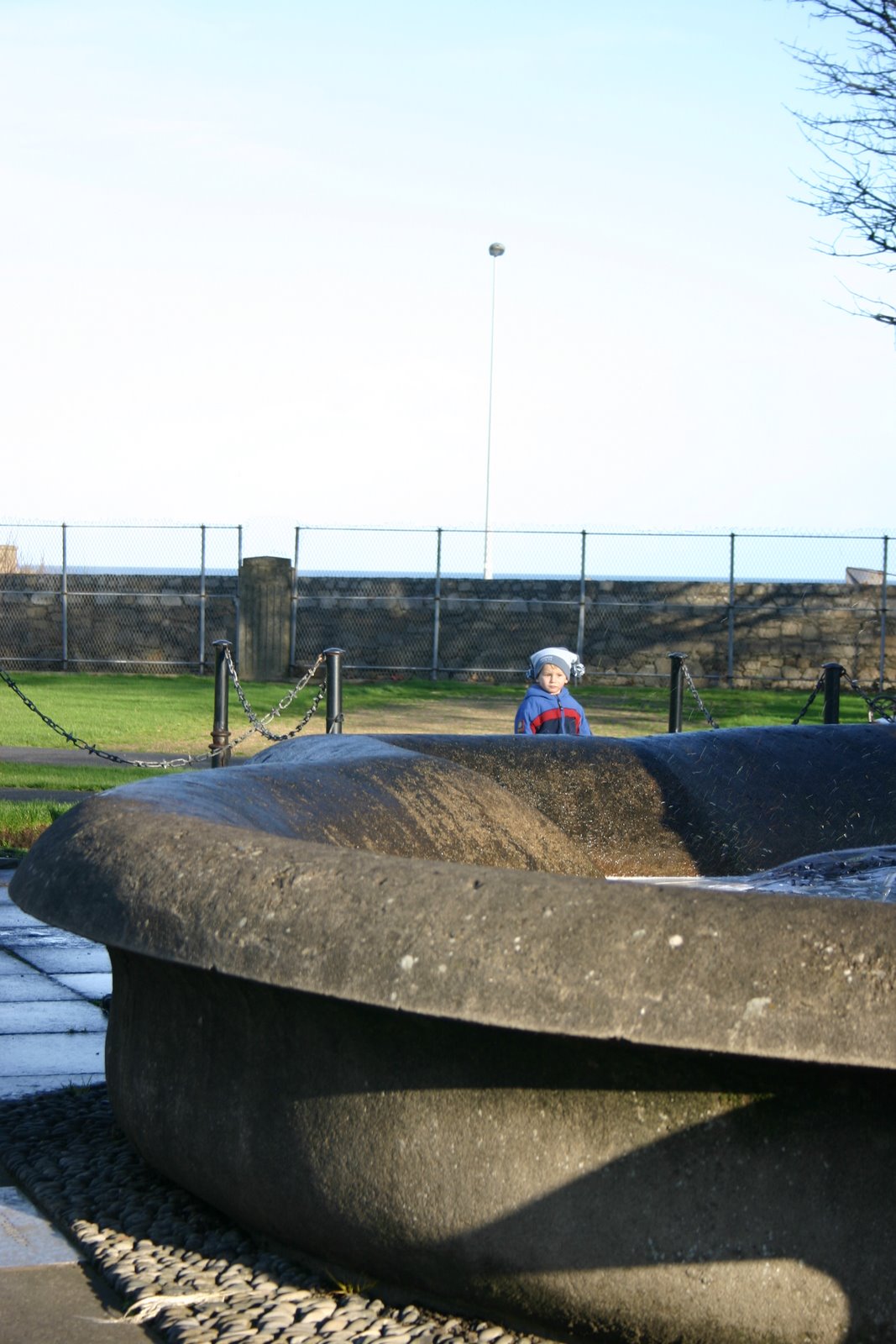 A fountain in a park.  Little boy in the background.