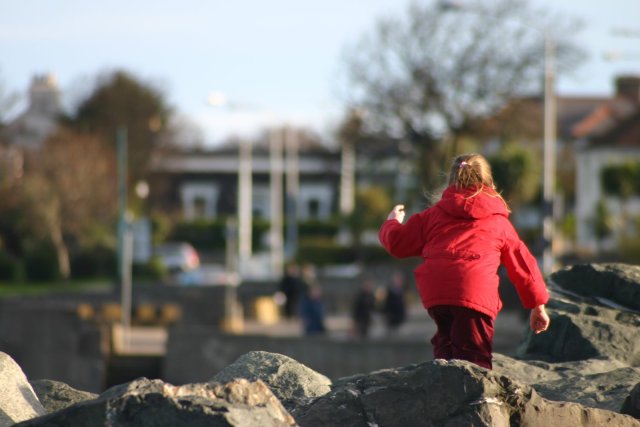 A little girl playing on the rocks.